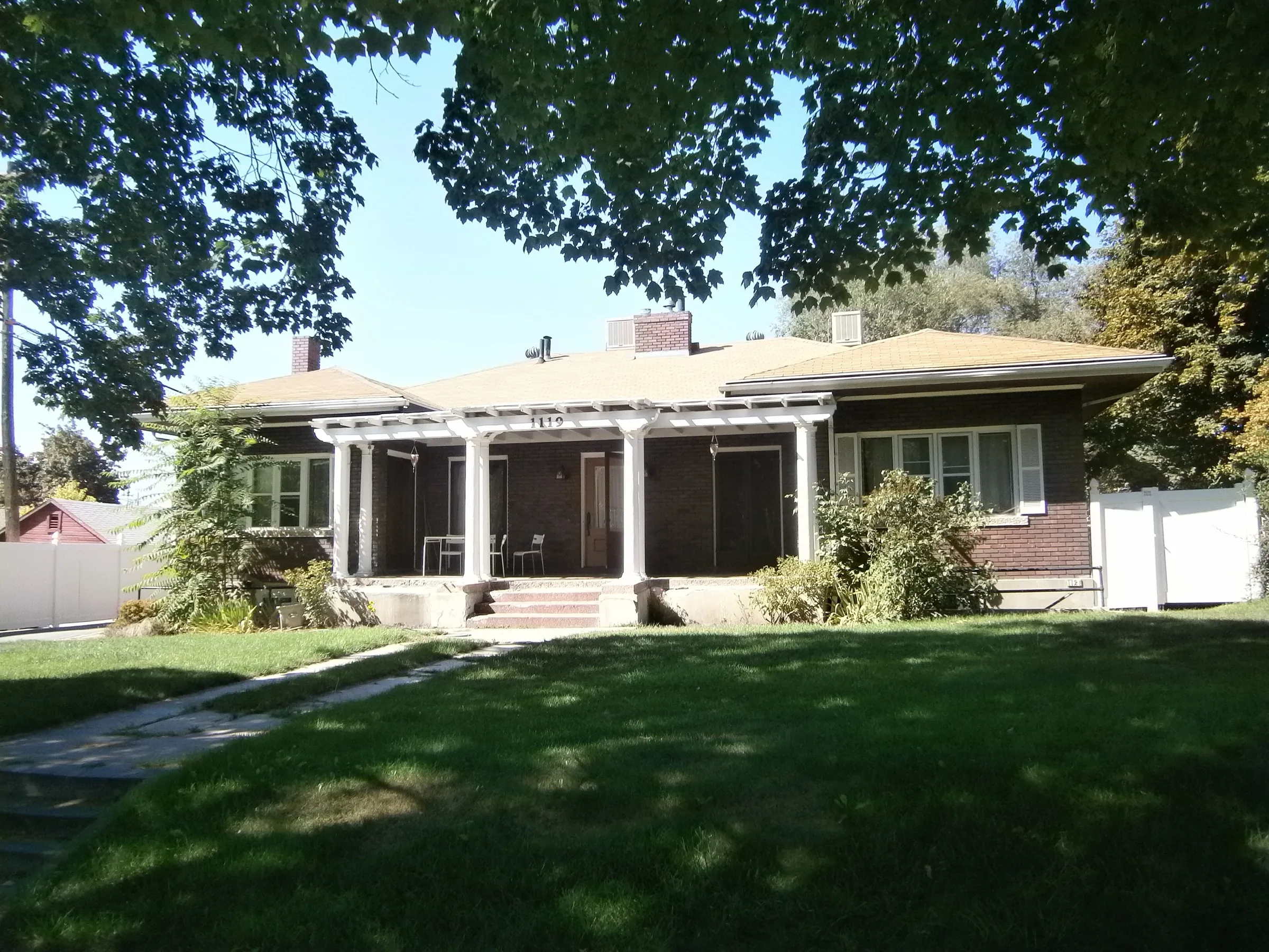 An open front lawn in front of a bungalow with clear sightlines to the porch.