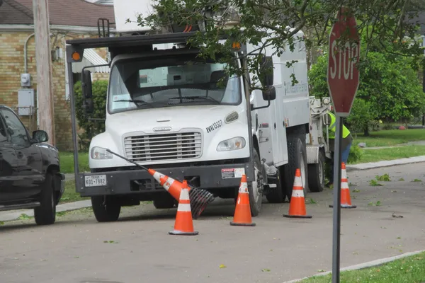 A bucket truck parked curbside behind cones.